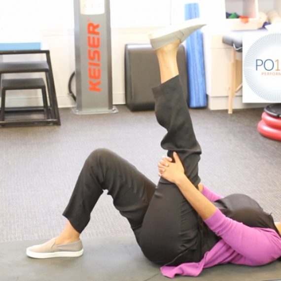 Physical therapist demonstrates hamstring stretch on floor